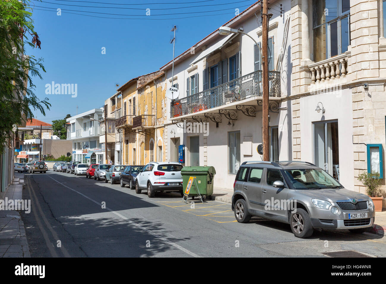 Cars parked on old narrow street with small houses. Paphos is a coastal popular summer tourist resort city in Cyprus. Stock Photo
