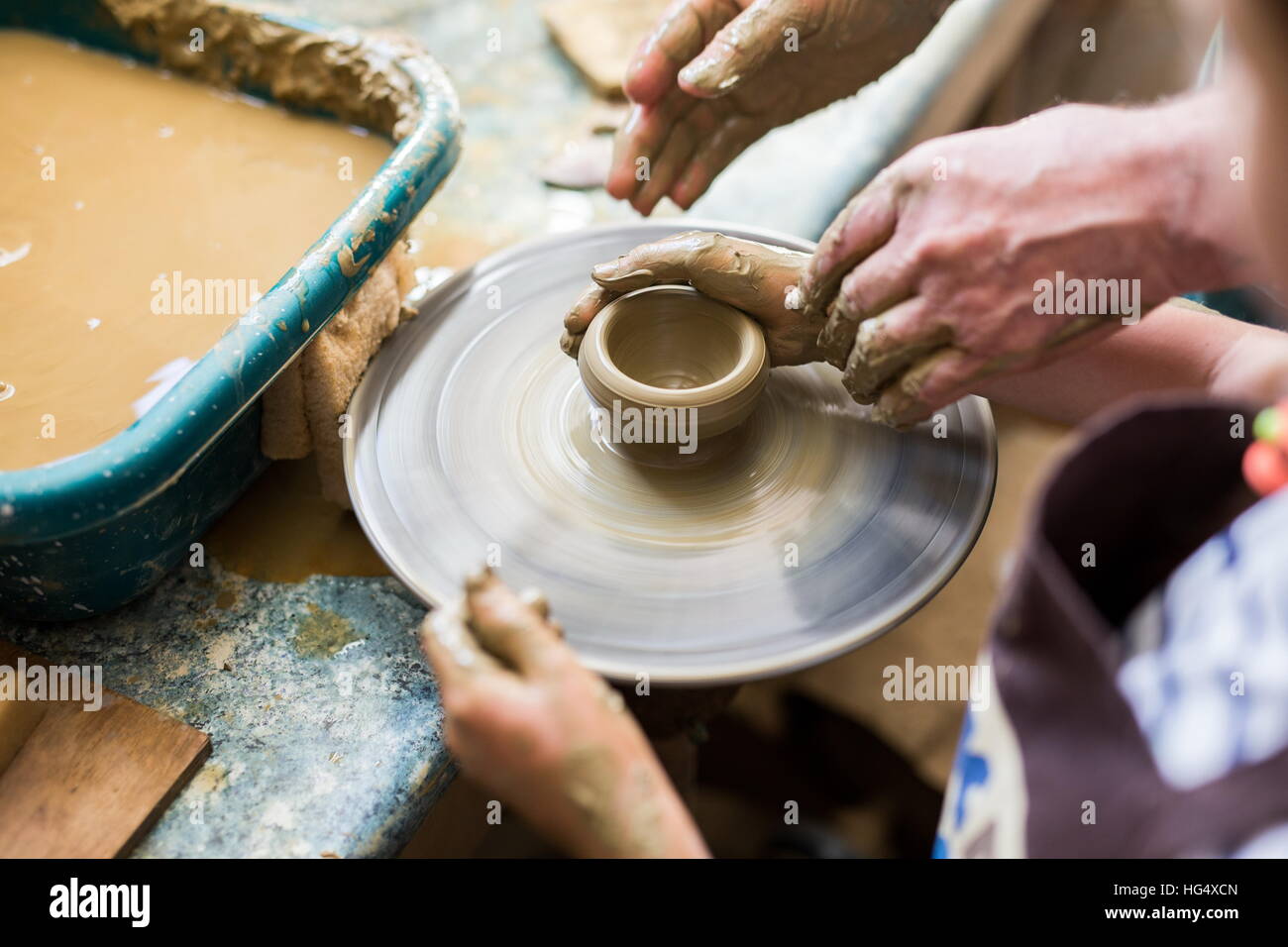 Senior potter teaching a little girl the art of pottery. Child working