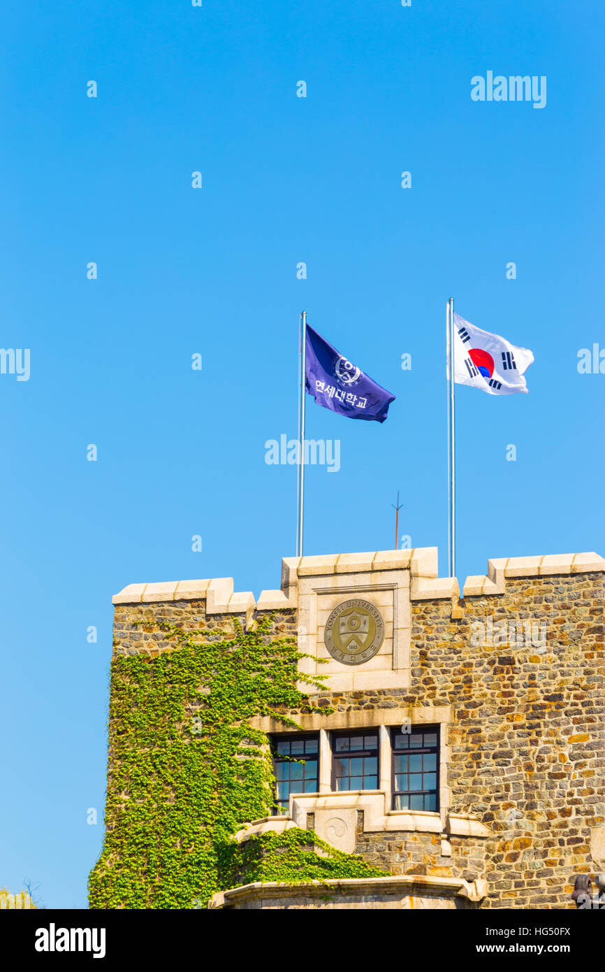 Yonsei University purple flag and Taegukgi Korean national flag flying above an ivy covered brick tower on a clear, blue sky day Stock Photo