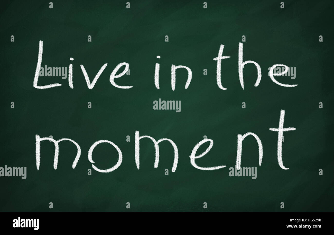 On the blackboard with chalk write Live in the moment Stock Photo