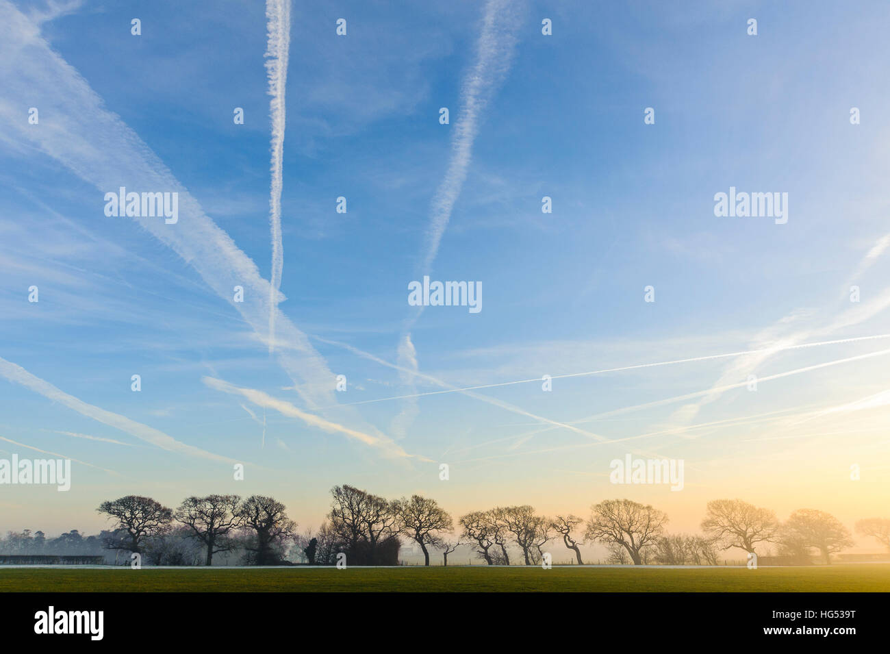 Vapour trails over misty fields and trees near Garstang Lancashire England Stock Photo