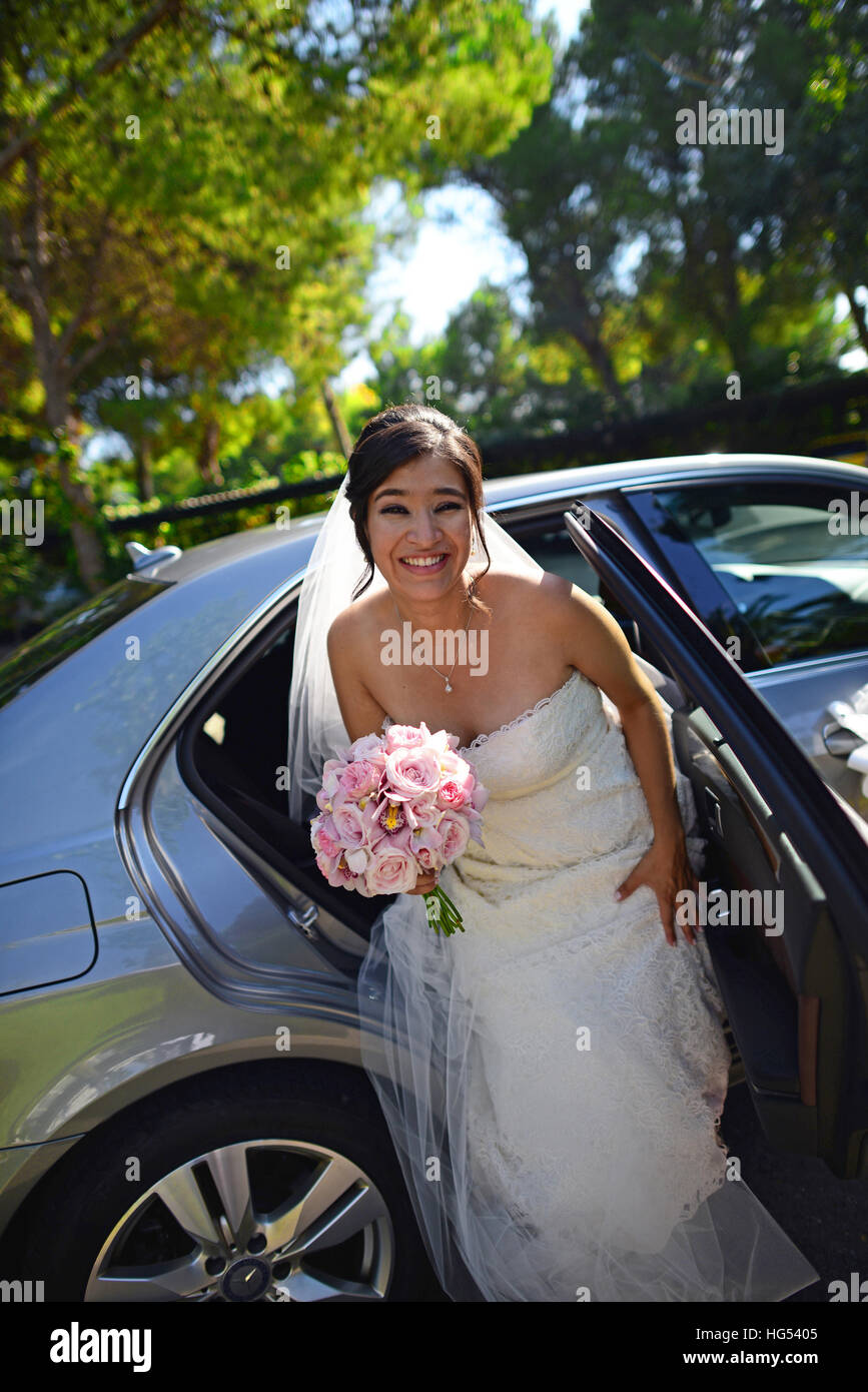 Latin bride getting out of wedding car with flower bouquet Stock Photo