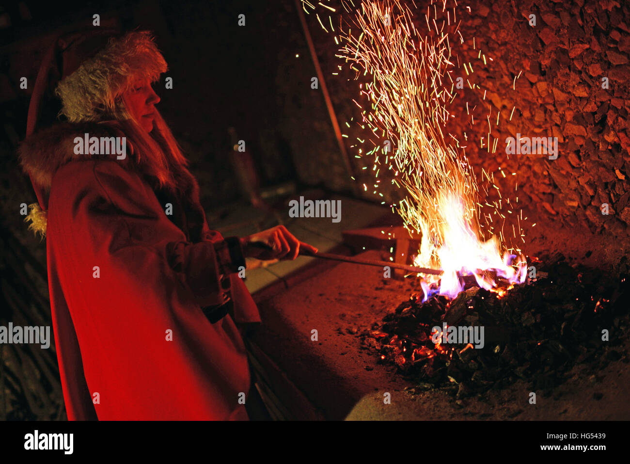 Young elf throws magical powders in the fire. Kakslauttanen Arctic Resort in Saariselka, Finland Stock Photo