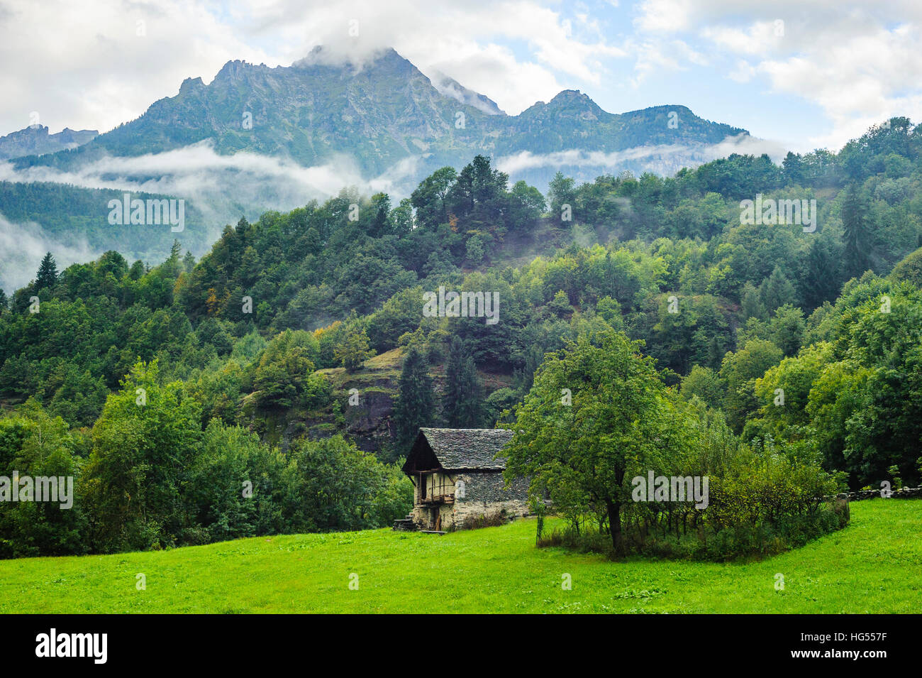 Alpine meadow and barn below misty mountains Parco Naturale Veglia Devero Piemonte Italy Stock Photo
