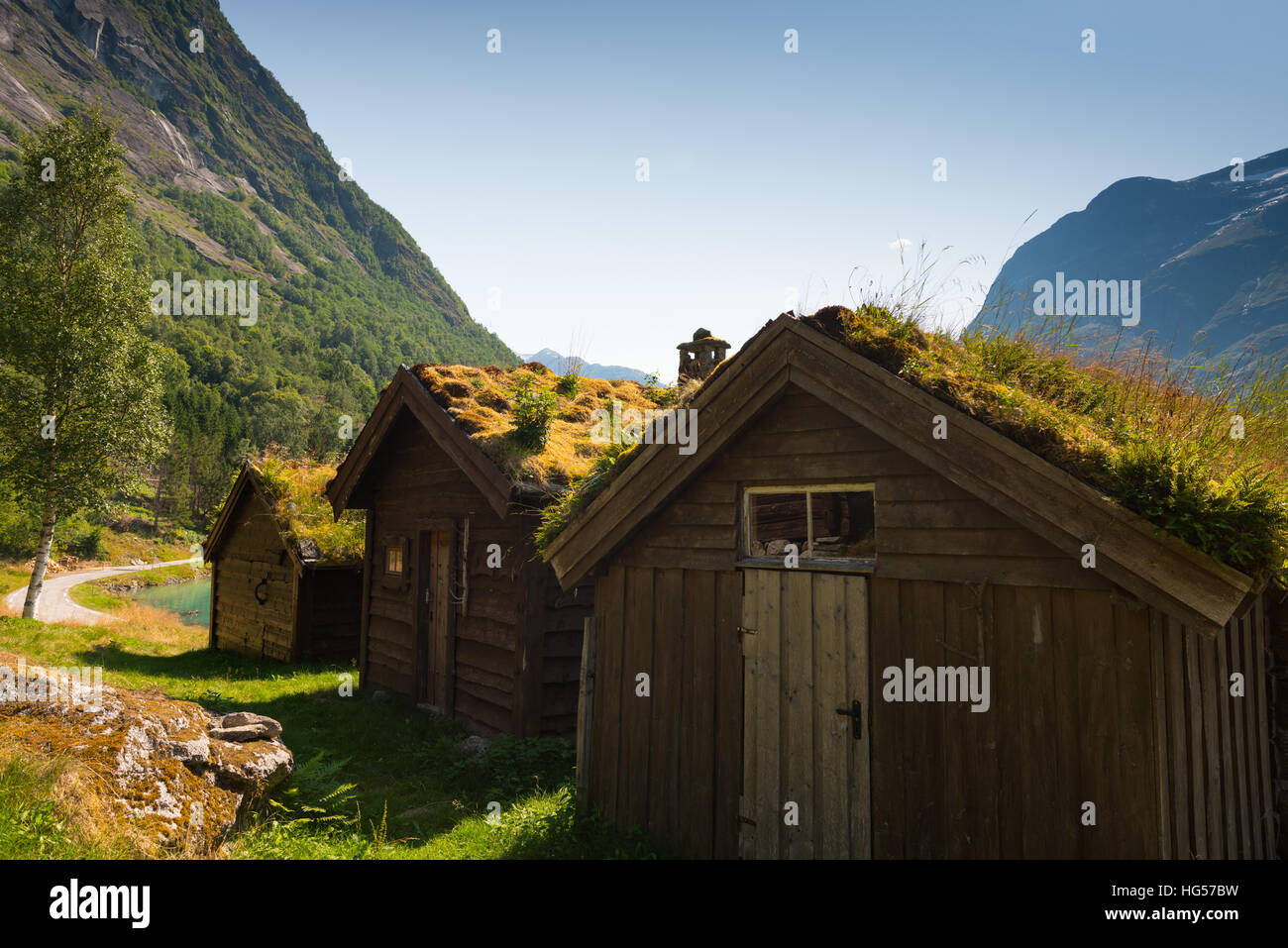 A view across Lovatnet Lake, a traditional Norwegian house sits in the foreground topped with sod roof. Stock Photo