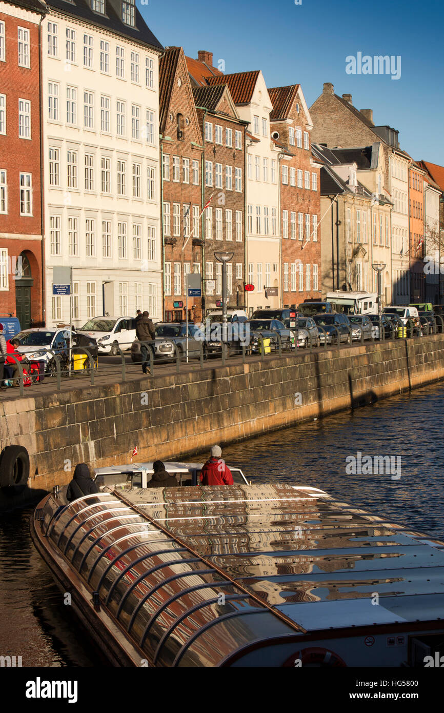 Denmark, Copenhagen, Nybrogade electric canal tour boat passing below canalside properties Stock Photo