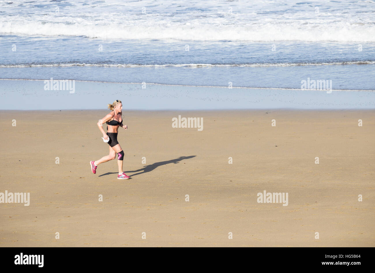 Mature woman running on beach. Stock Photo