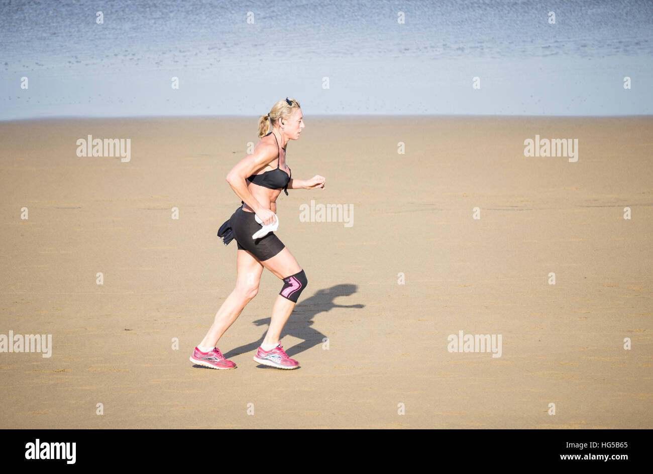 Mature woman running on beach. Stock Photo