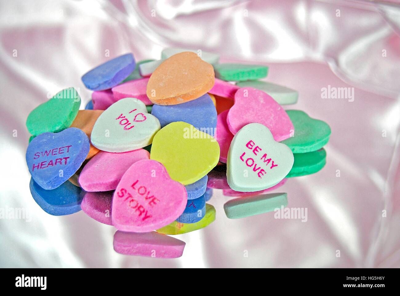 valentine candy hearts on mirror and pink satin Stock Photo