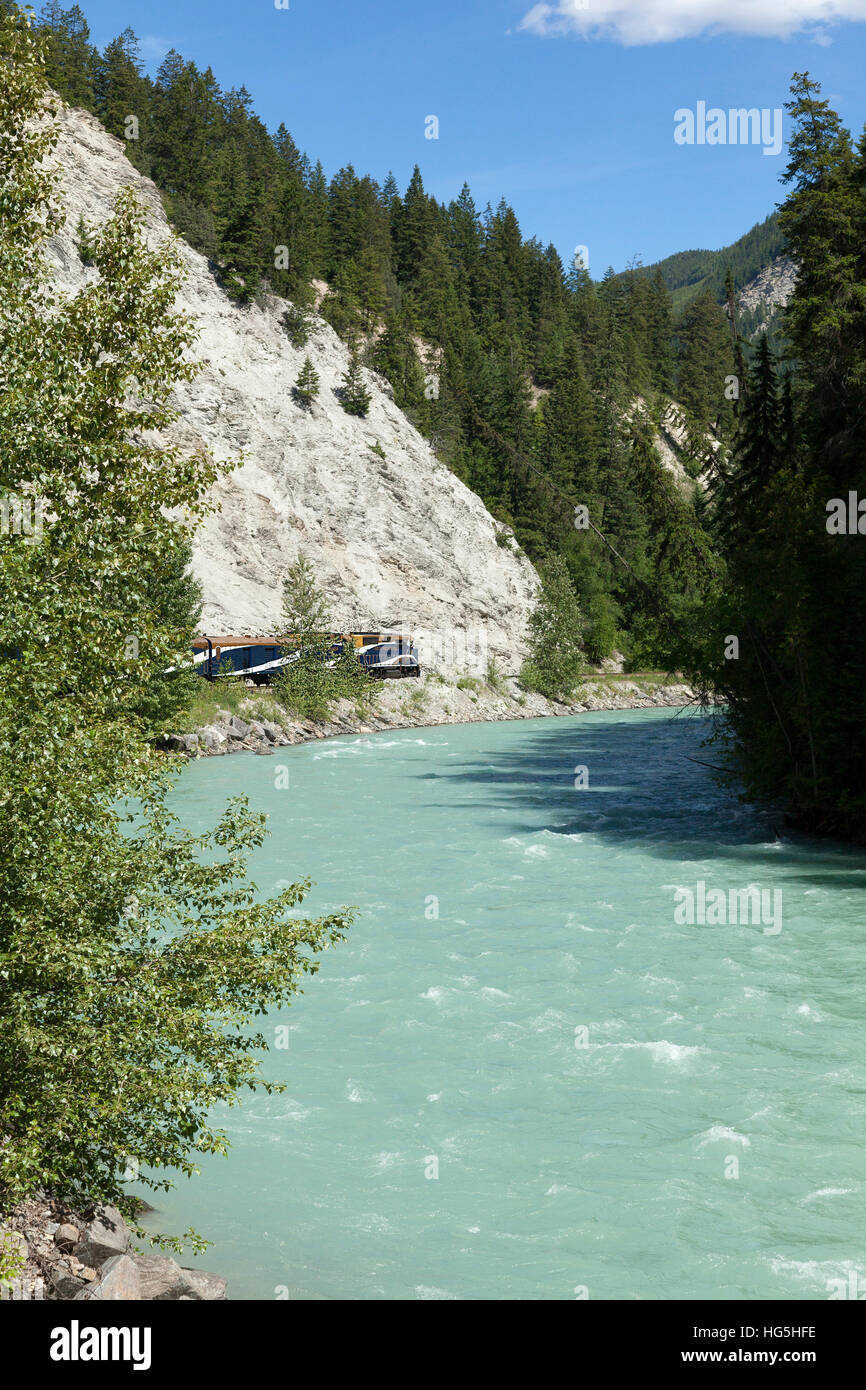 The Rocky Mountaineer train on the Canadian Pacific Rail route through the Rocky Mountains, Canada near Vancouver. A wild river is in the foreground. Stock Photo