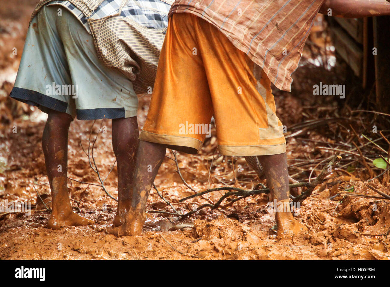 Two Malagasy men trying to push car from a deep mud Stock Photo