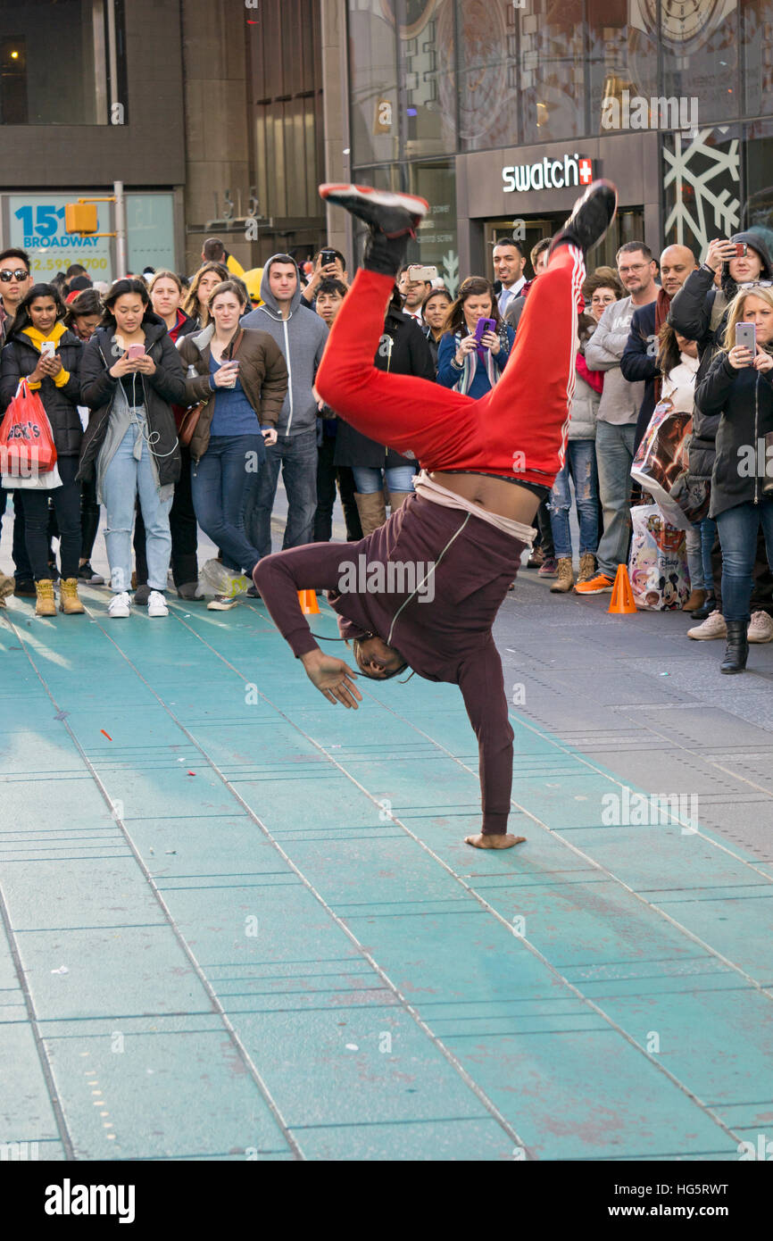 An acrobatic athletic street  busker in Times Square balancing himself on his hand in midtown Manhattan, New York City Stock Photo