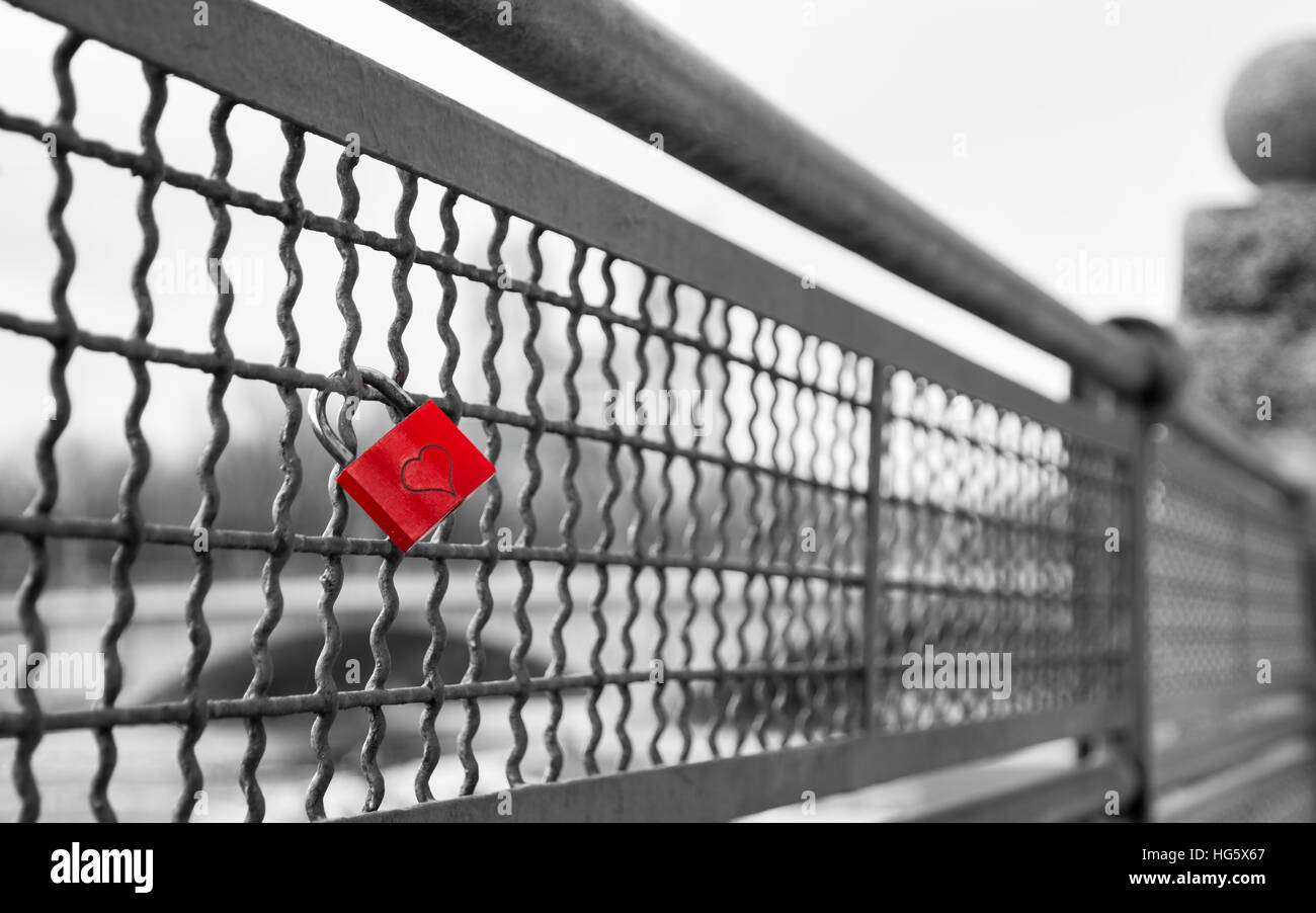 Love lock with heart shape on the bridge as symbol of infinite true love. Black and white stock photo with selective red color Stock Photo