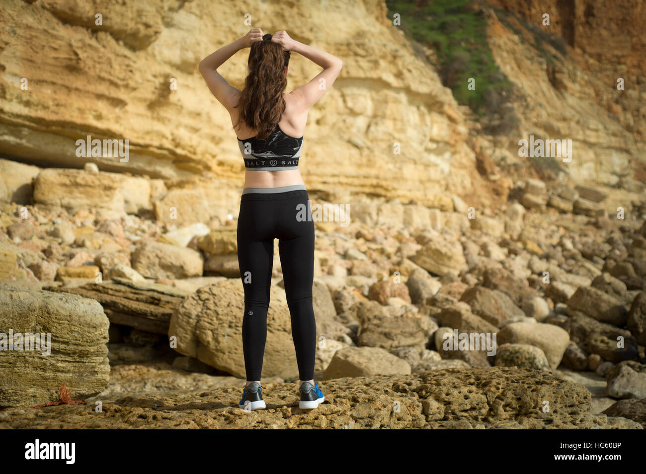 woman adjusting her ponytail while exercising at the beach Stock Photo