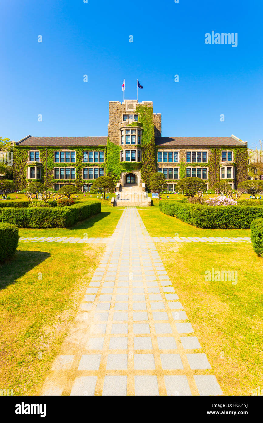 Grassy footpath leading to ivy covered main building at venerable Yonsei University in Sinchon, Seoul, South Korea. Vertical Stock Photo