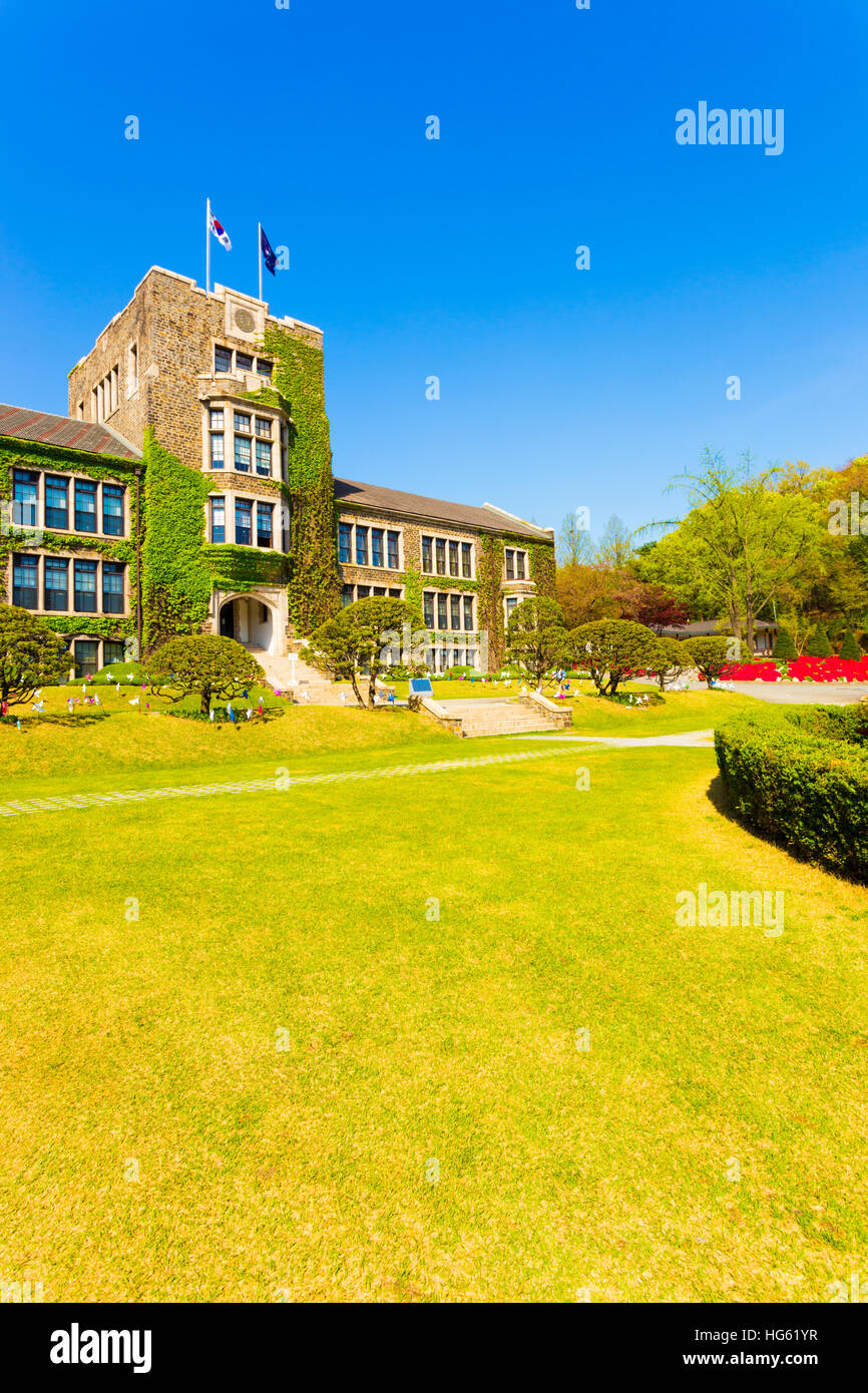 Flags flying over ivy covered main building above grassy quad at Yonsei University on a blue sky day in Sinchon, Seoul, Korea Stock Photo