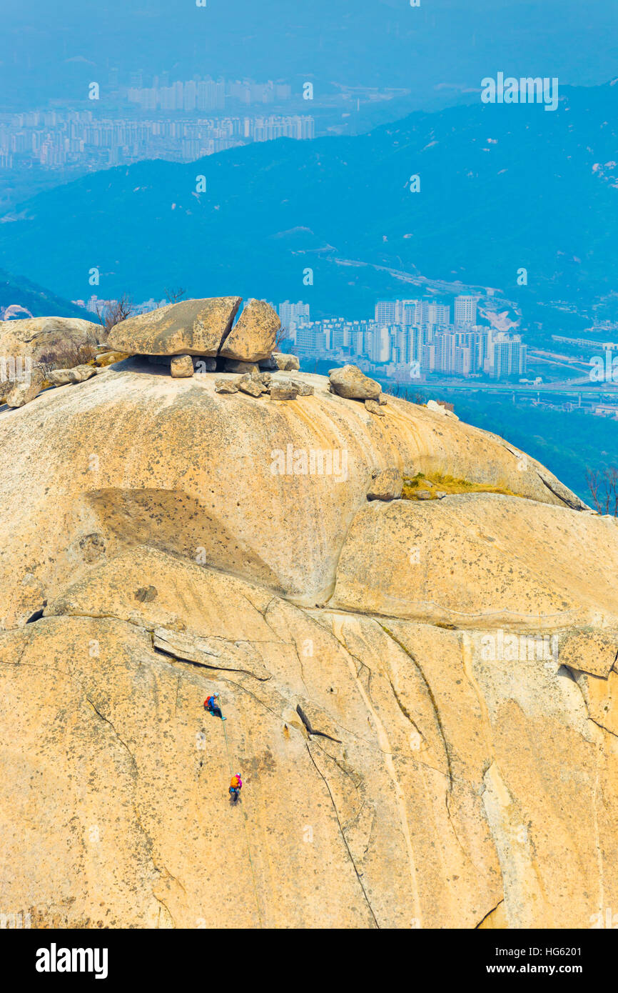 Mountain climbers climbing Insubong peak in Bukhansan mountain with view of valley below in Seoul, South Korea Stock Photo