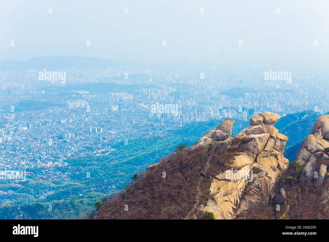 View of Seoul cityscape from peak of Bukhansan mountain where smog and air pollution prevents clear view buildings Stock Photo