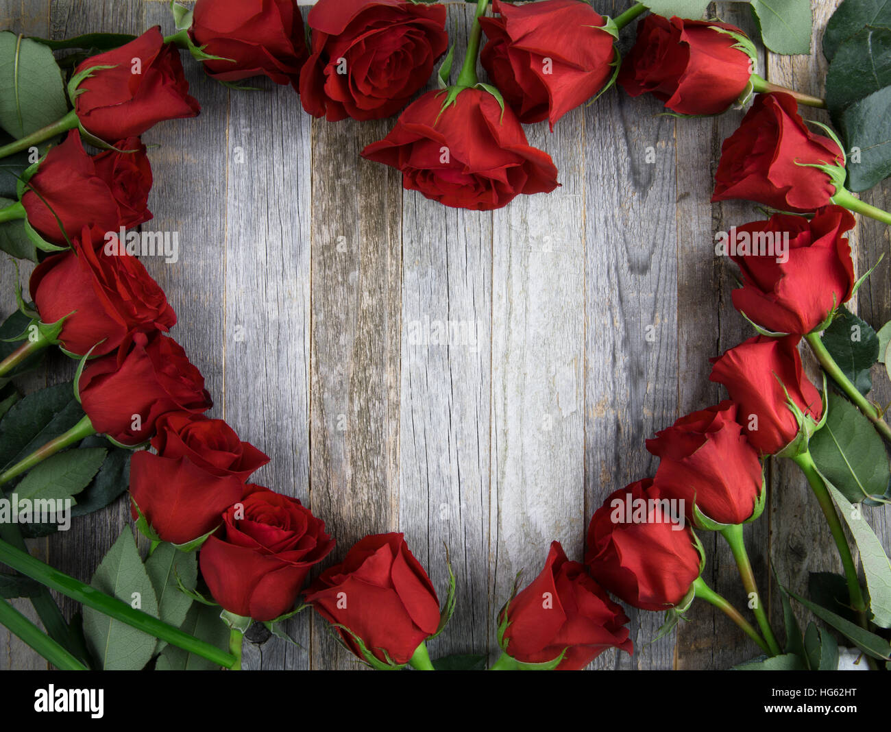 Red rose heart shape frame with copy space on wooden background. Stock Photo