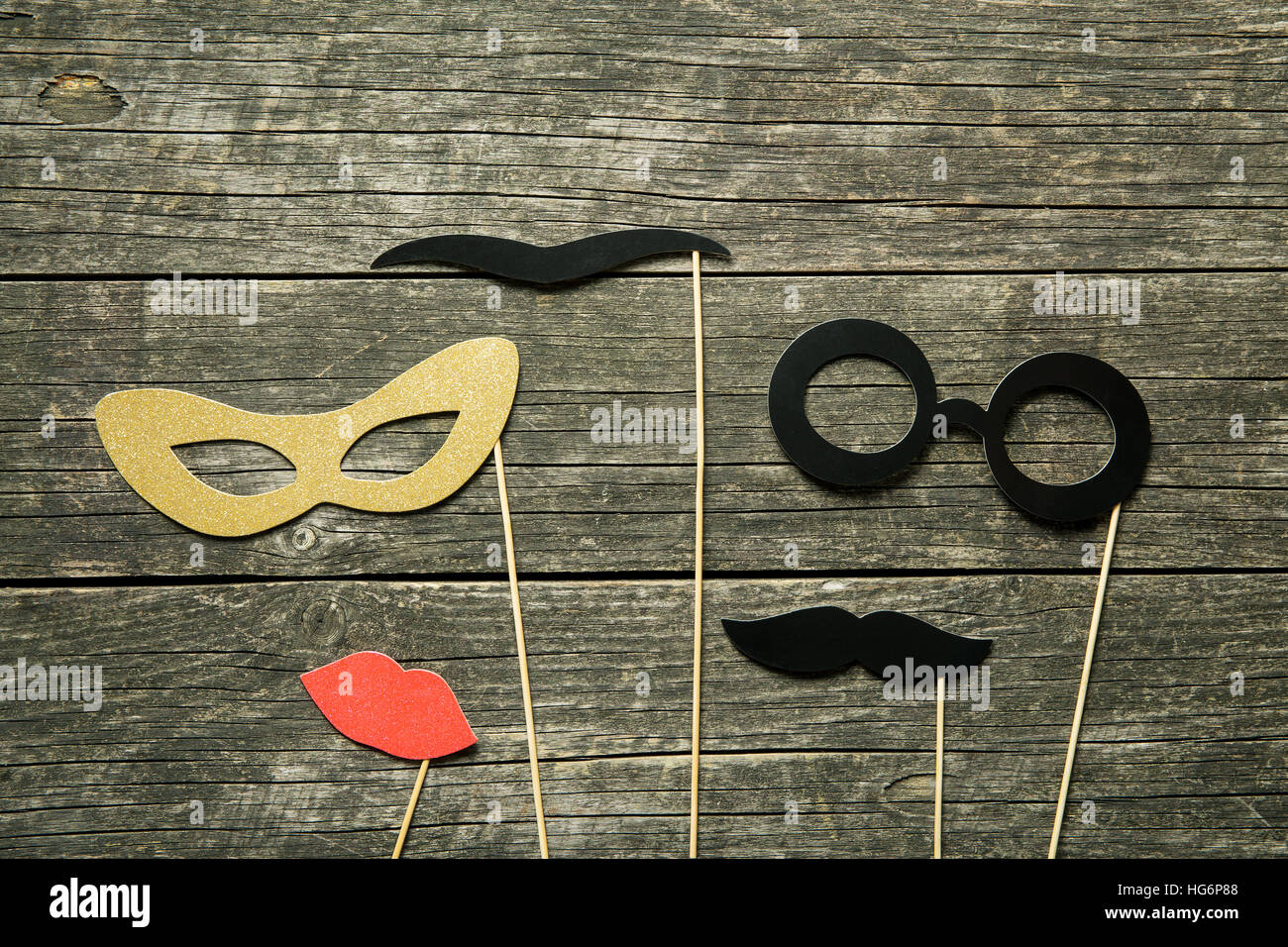 Fake lips, glasses and mustaches on sticks on old wooden background. Stock Photo