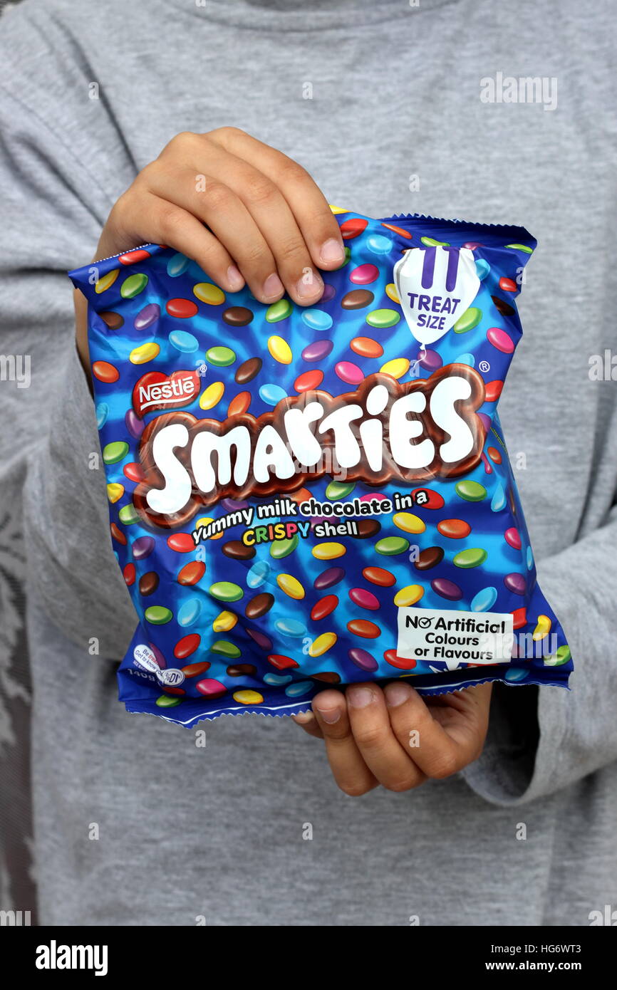 Close up of a child holding a bag of Nestle Smarties Stock Photo