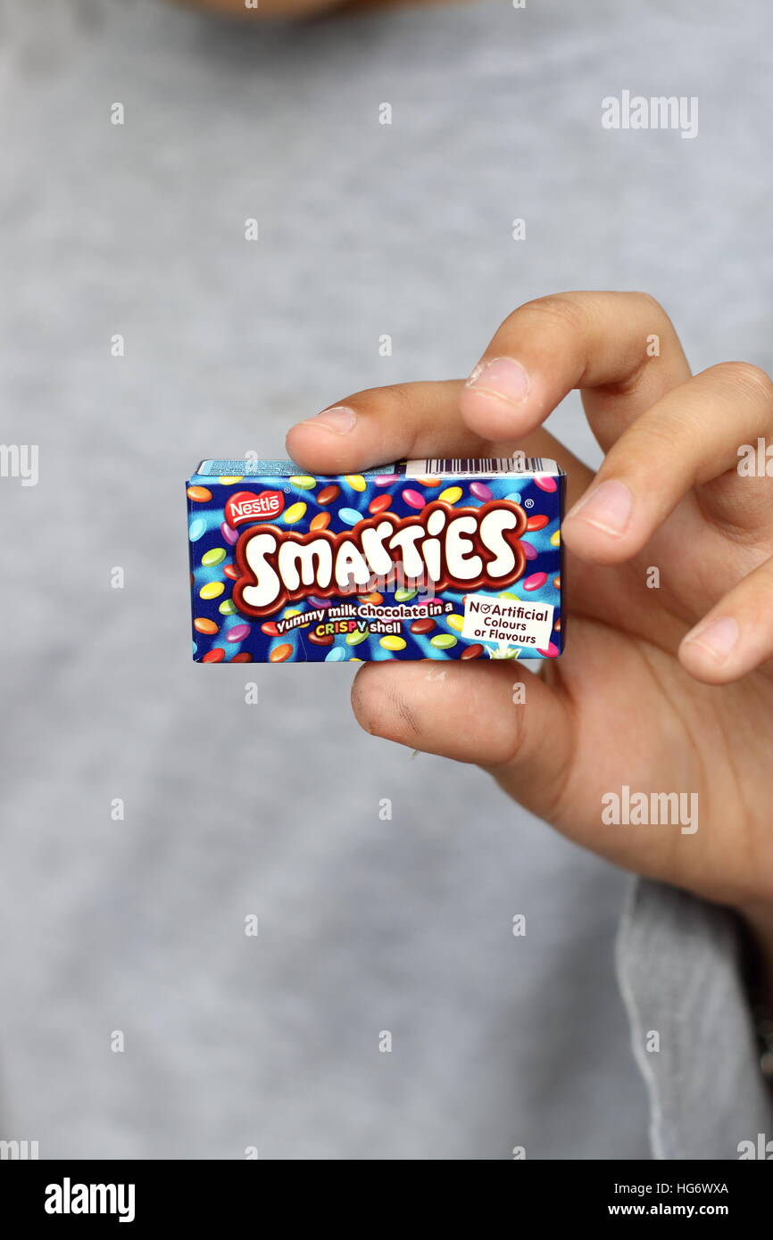Close up of left hand holding Nestle Smarties isolated Stock Photo