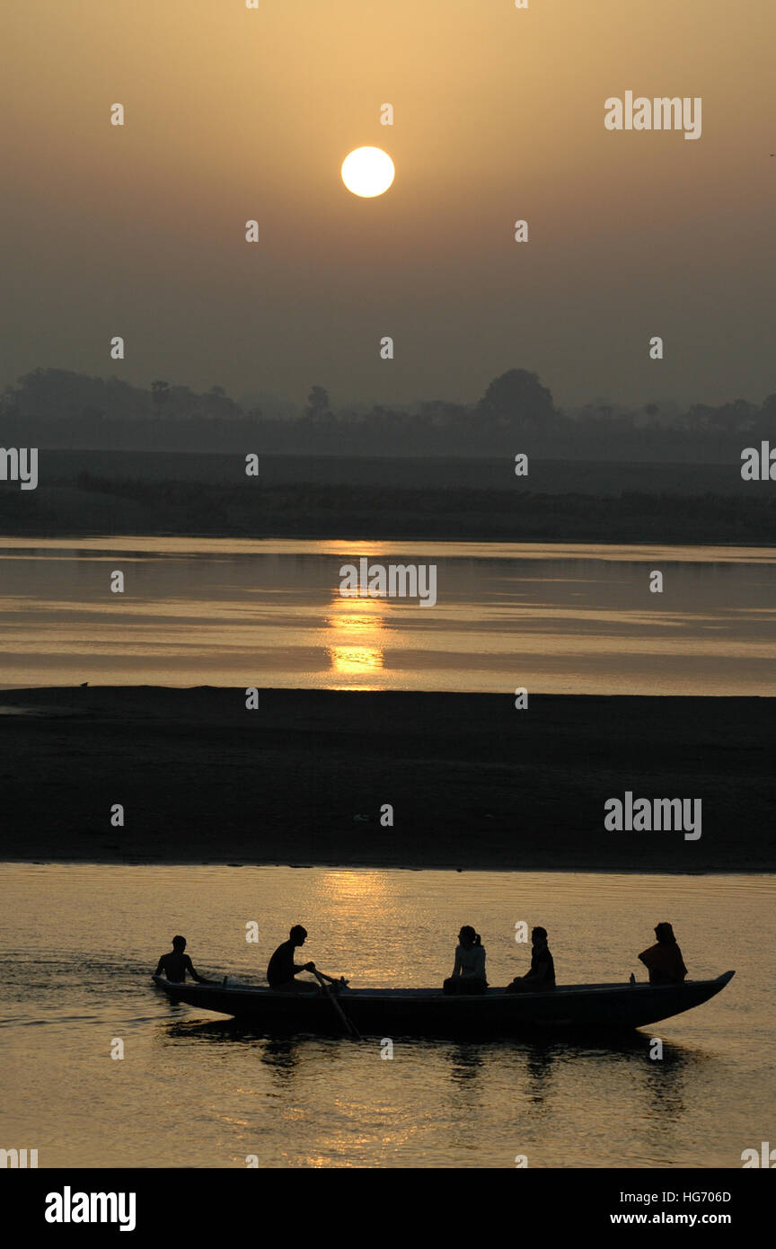 Silhouette of people in a boat at sunrise over the Ganges river in Varanasi India Stock Photo