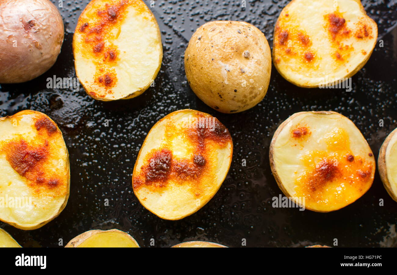 Roasted potato slices on a black baking plate Stock Photo