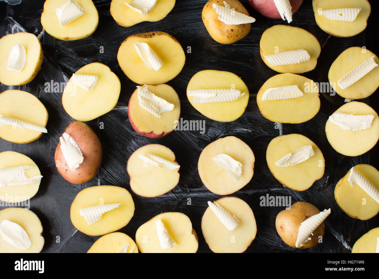 Raw potato with butter on black baking plate Stock Photo
