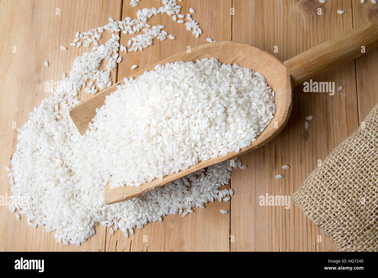 Rice falling out from big wooden spoon Stock Photo