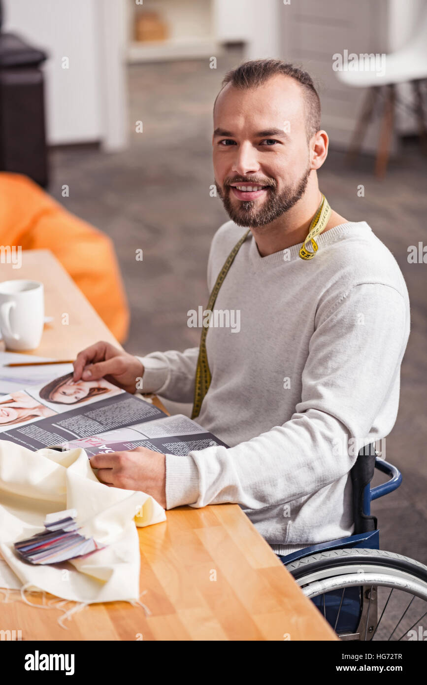 Enthusiastic handicapped dressmaker reading fashion magazines Stock Photo
