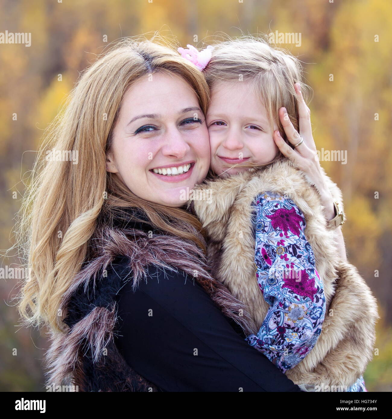 Happy mother hug her daughter in autumn background Stock Photo