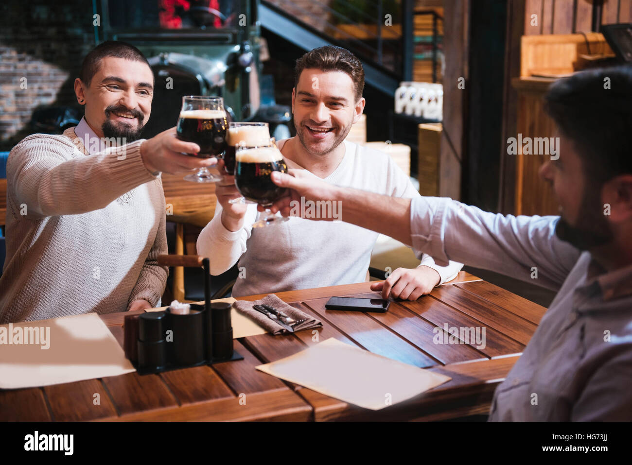 Cheerful happy men clinking their glasses Stock Photo - Alamy