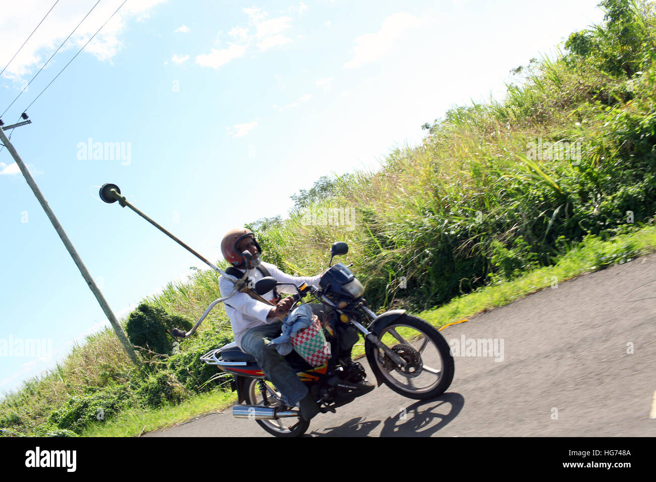 Man travels with garden strimmer on motor bike Stock Photo