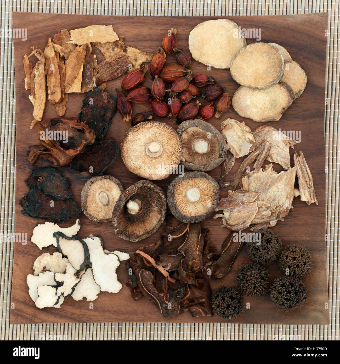 Chinese herbal medicine selection on maple wood board on bamboo background. Stock Photo