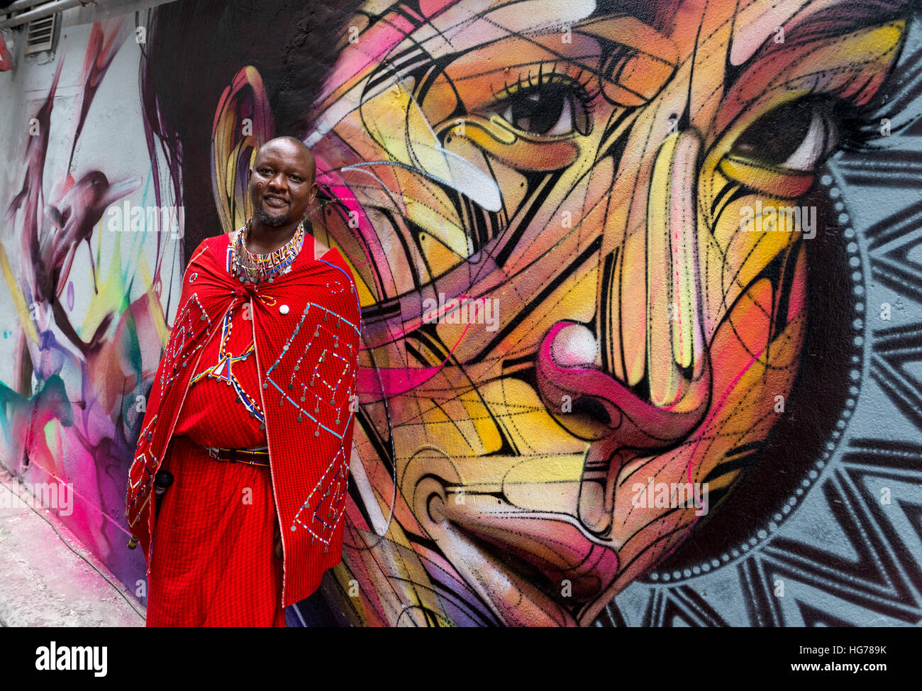 Masai warrior Daniel Ole Sambu stands in front of a wall painting by Parisian street artist Alexandre Monteiro aka Hopare of Hong Kong actress and can Stock Photo