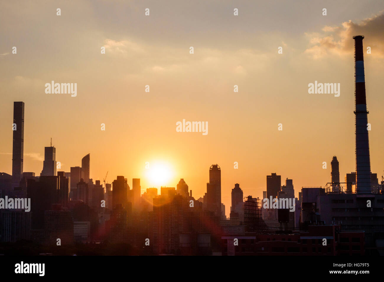 New York City,NY NYC Queens,Long Island City,view,Manhattan skyline,buildings,sunset,sunrays,orange,yellow,silhouette,chimney,NY160723094 Stock Photo