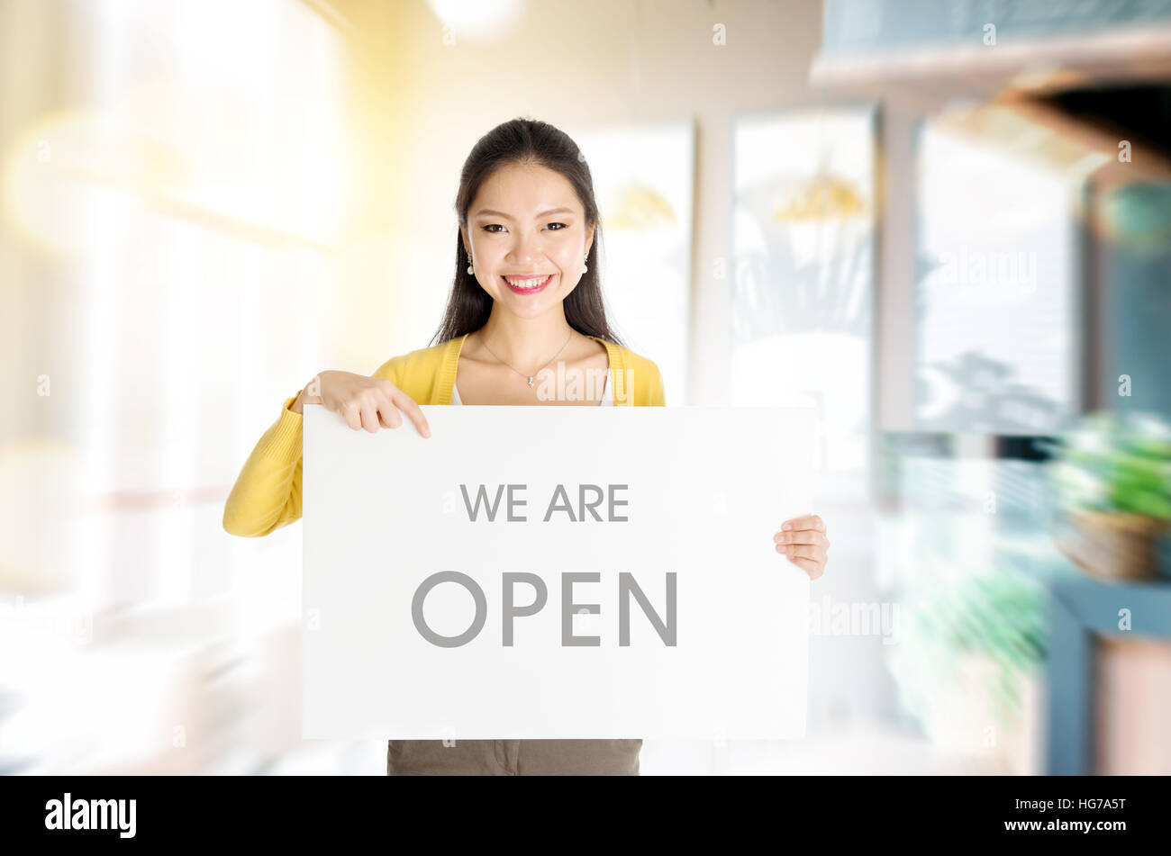 Young Asian woman hand holding 'we are open' sign board in restaurant or cafe. Stock Photo