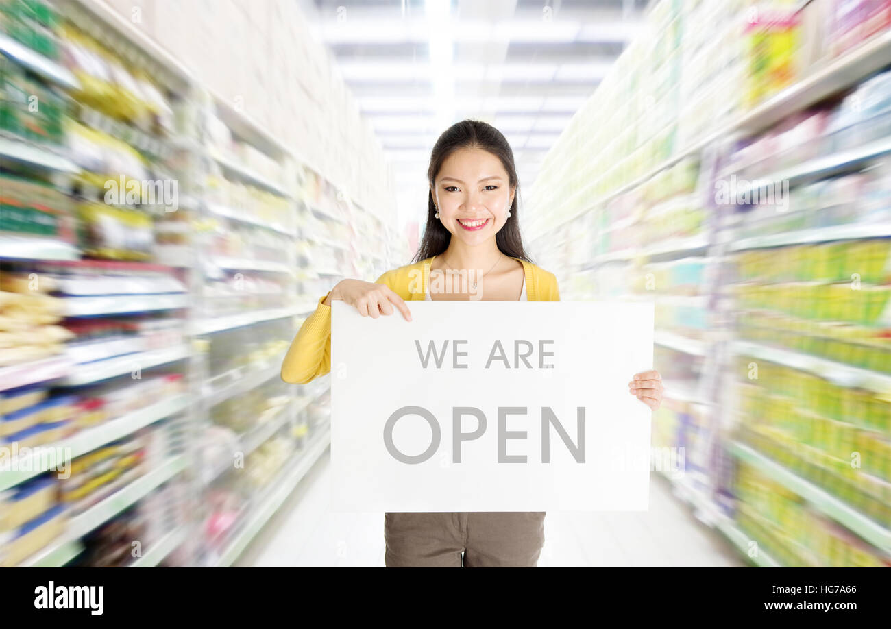 Young Asian woman hand holding 'we are open' sign board in market or department store. Stock Photo