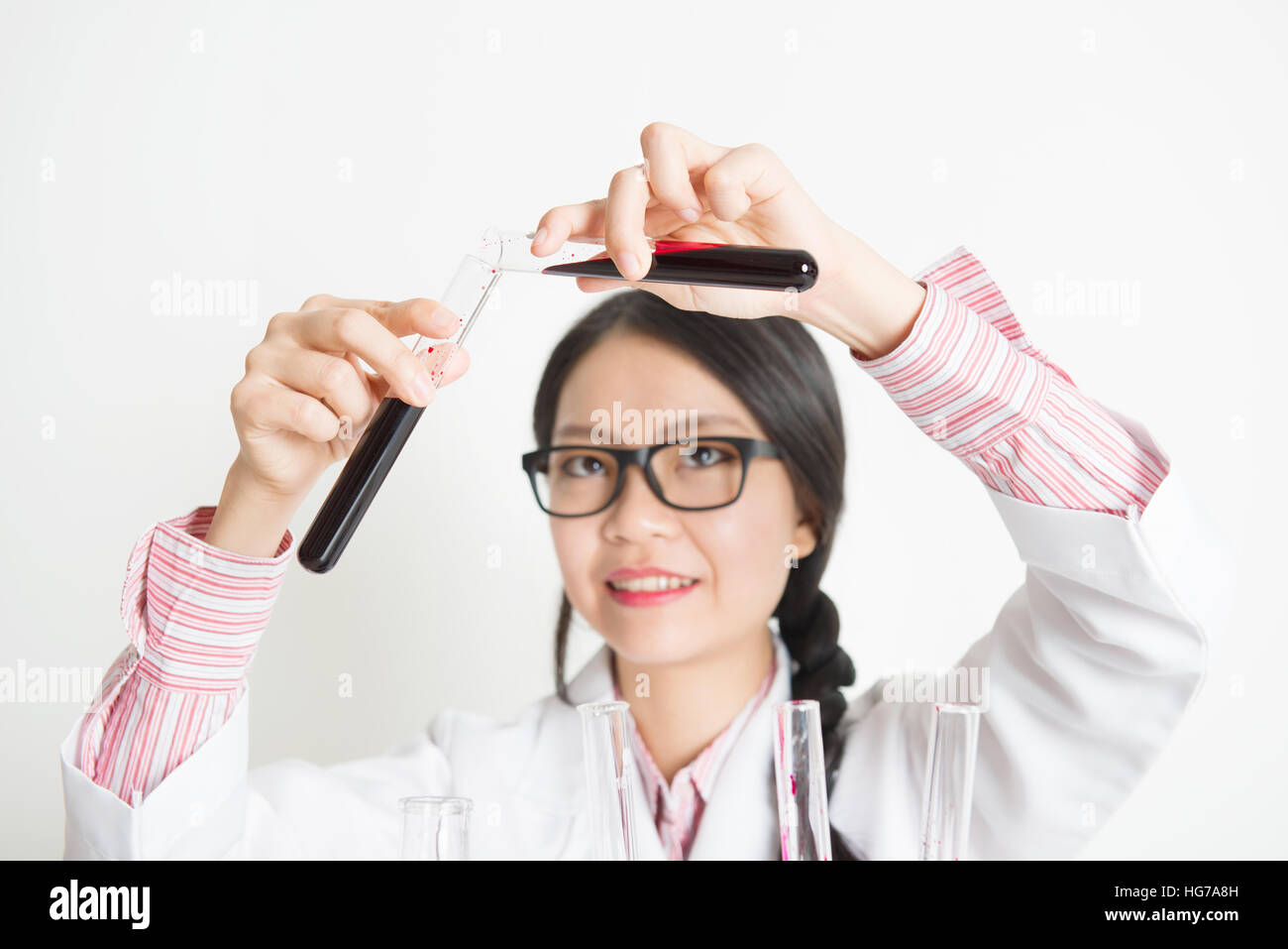 Young Asian female researcher looking at the tube in laboratory. Stock Photo