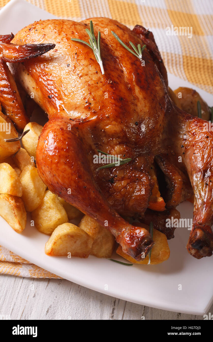 whole roast chicken and fried potatoes closeup on a plate. vertical