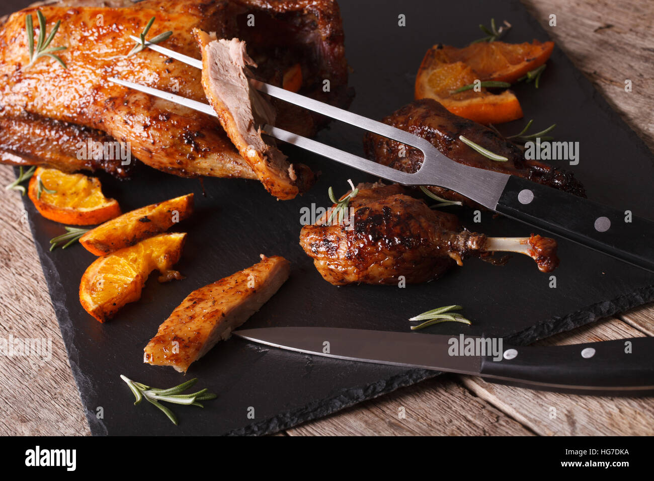 Cutting the roast duck close up on a black slate board. Horizontal