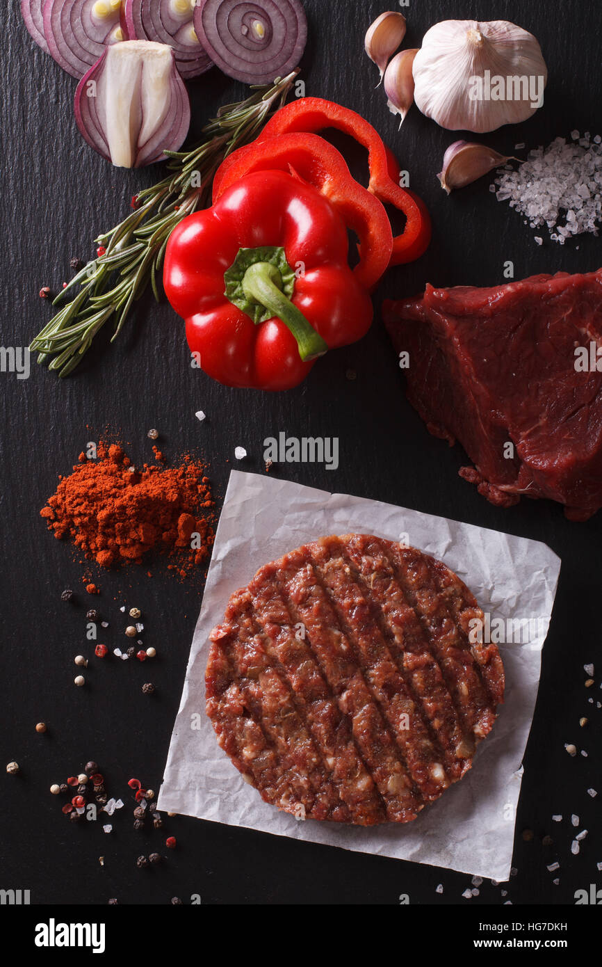 Raw Ground beef meat Burger steak cutlets with ingredients on the board closeup. vertical view from above Stock Photo