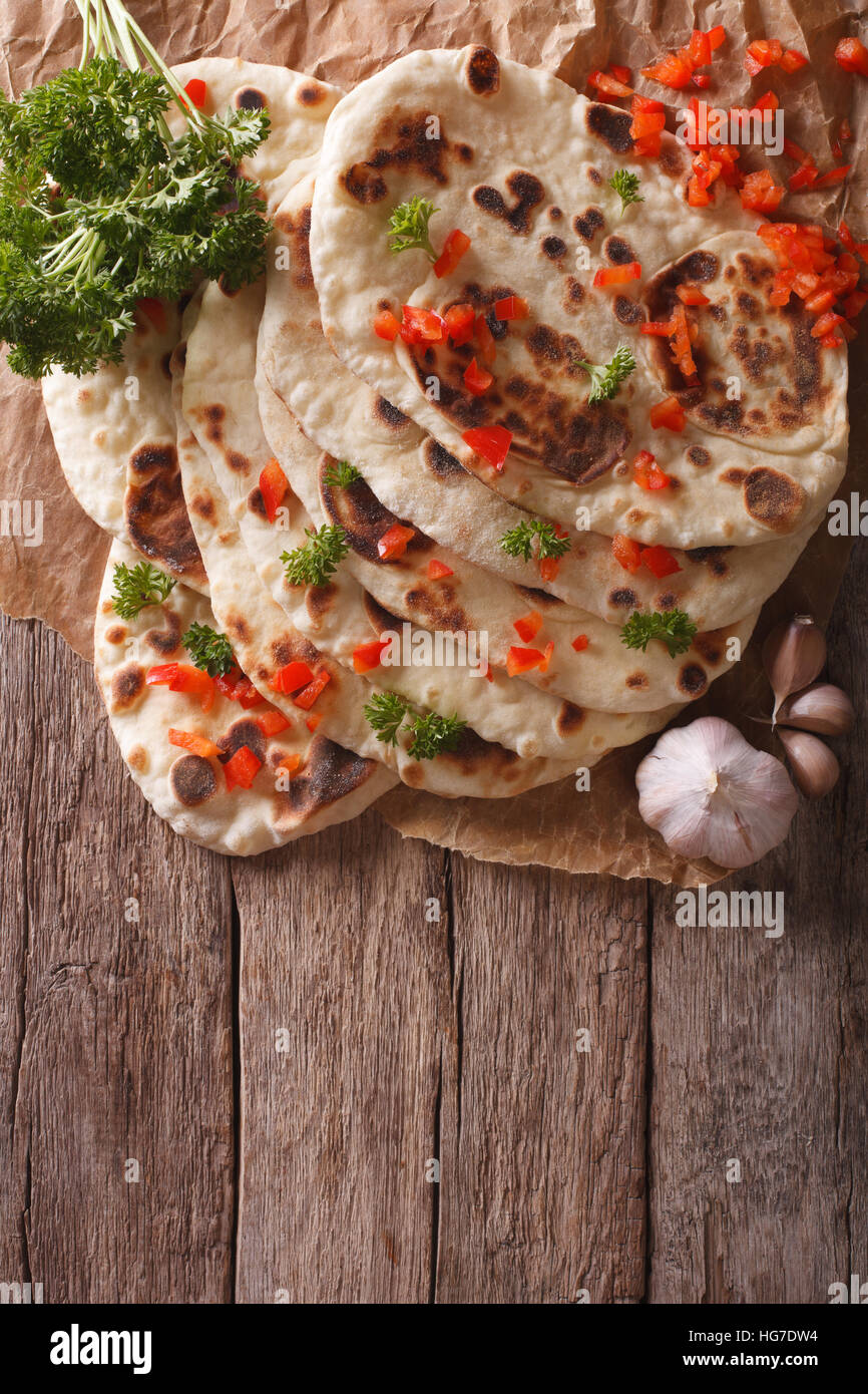 Indian Naan flat bread with garlic and herbs on the table. vertical top