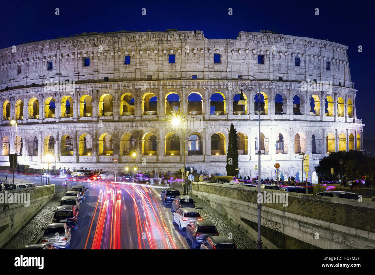 Long exposure to the Colosseum, taken at night with the shining path of cars. Front view of the Colosseum facade. Stock Photo