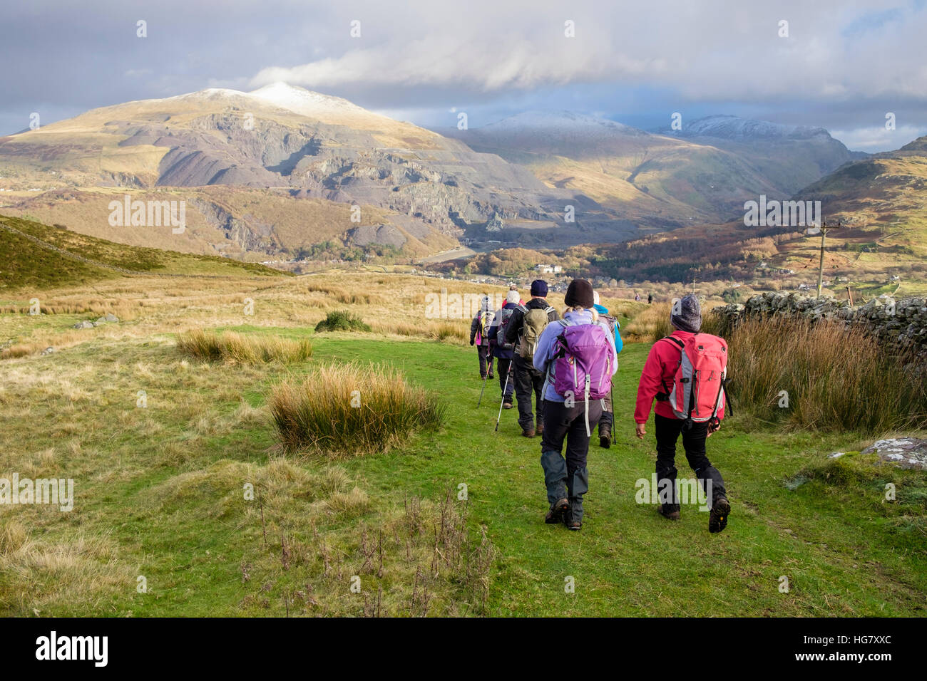 Hikers hiking on track from Bwlch y Groes in Snowdonia with view to Elidir Fawr and Dinorwig slate quarry above Llanberis, Gwynedd, Wales, UK, Britain Stock Photo