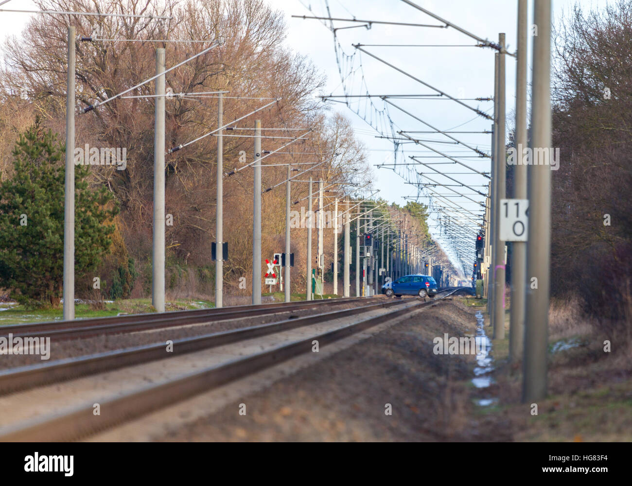 blue car drives over a railroad crossing Stock Photo