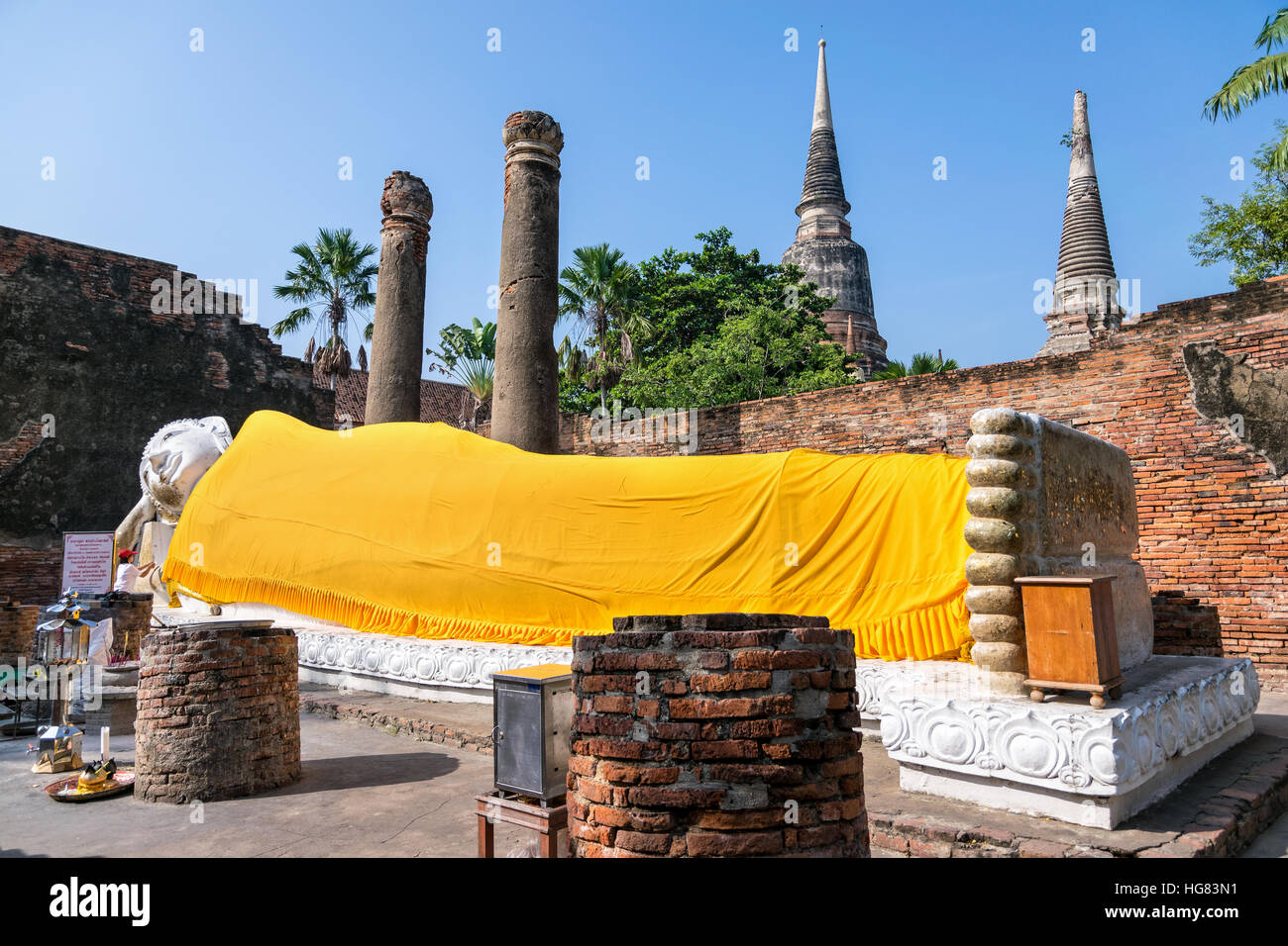 Buddha statues are white covered with yellow robe poses sleep amidst ancient ruins at Wat Yai Chai Mongkon temple in Phra Nakhon Si Ayutthaya Stock Photo