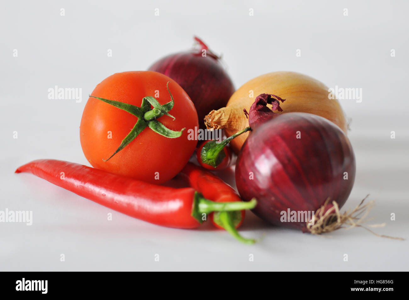Tomato, red paper and onion on a white background close-up of the reflection Stock Photo
