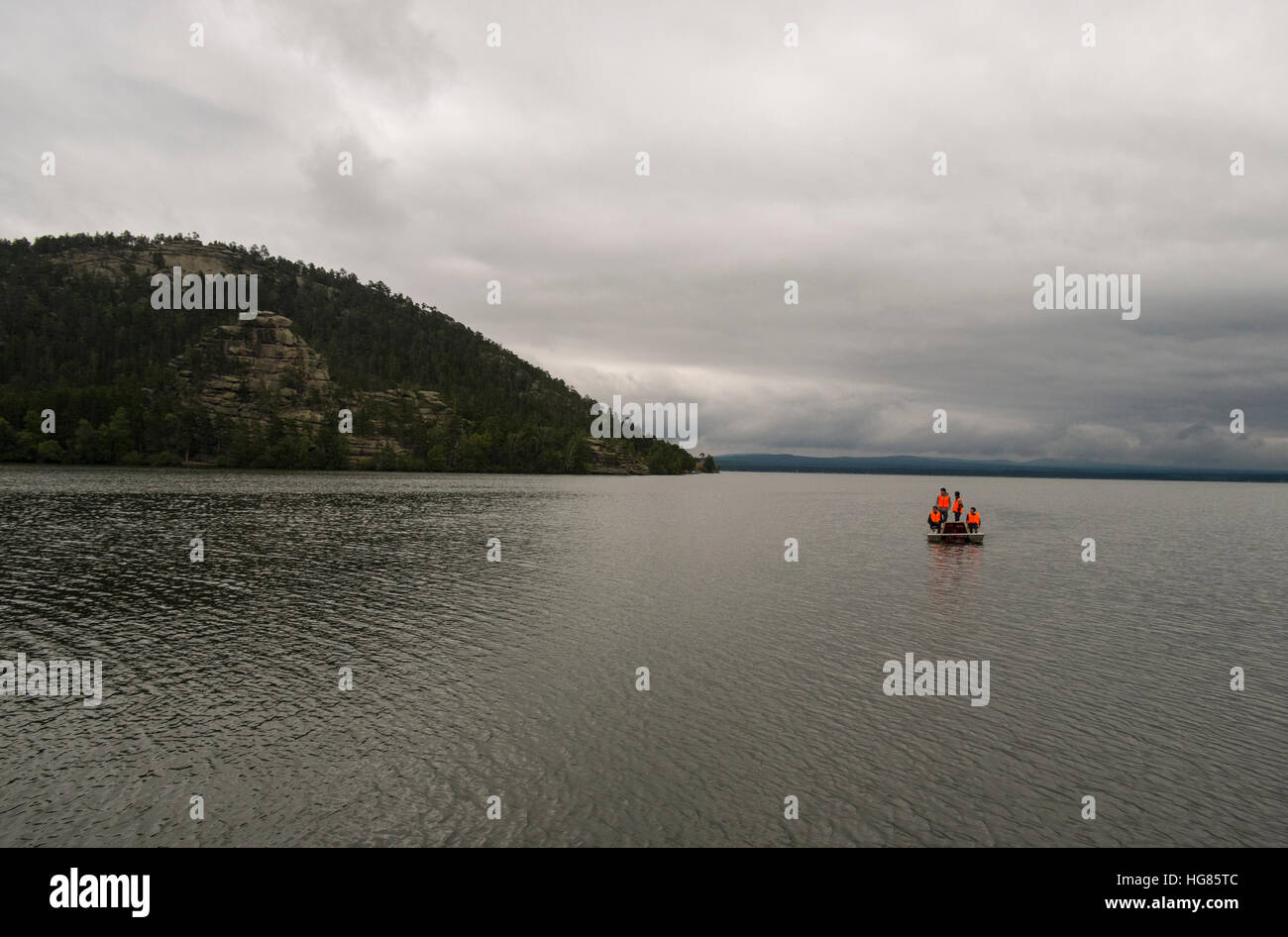 Mid distance view of friends boating in river against cloudy sky Stock Photo